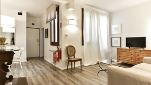 Uma sala de estar moderna com sofá, aparador de madeira, televisão e área de jantar com cadeiras e mesa.