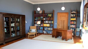 Een bibliotheek met houten boekenkasten, een bureau en een stoel.