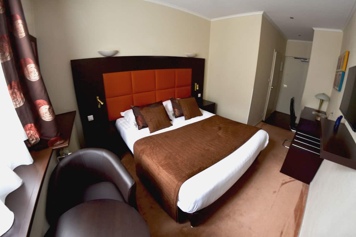 Quarto de hotel com uma cama grande, uma escrivaninha e uma cadeira.