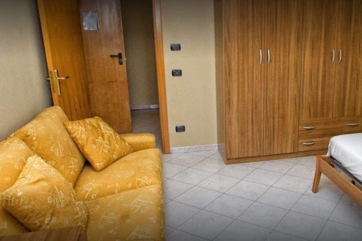 A hotel room with a bed, a wardrobe, and a sofa.