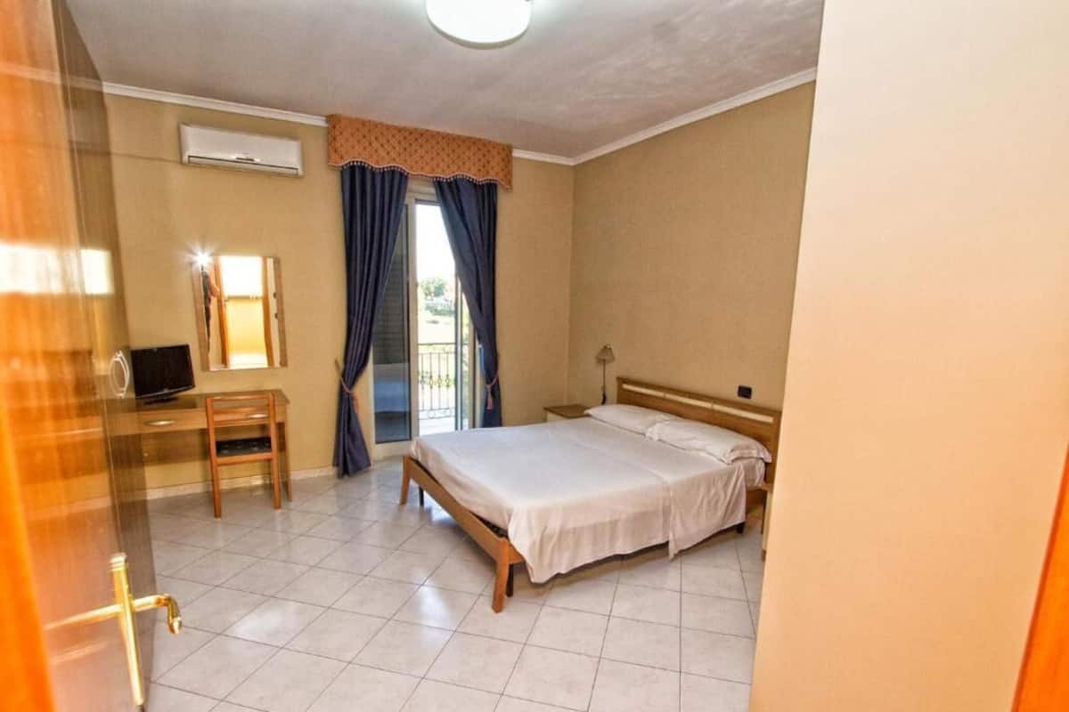 A hotel room with a bed, a desk, and a chair.