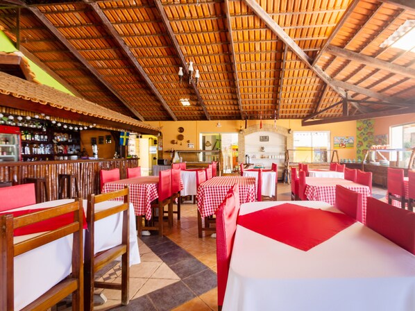 Un restaurante con manteles a cuadros rojos y blancos, sillas de madera y un alto techo de madera.