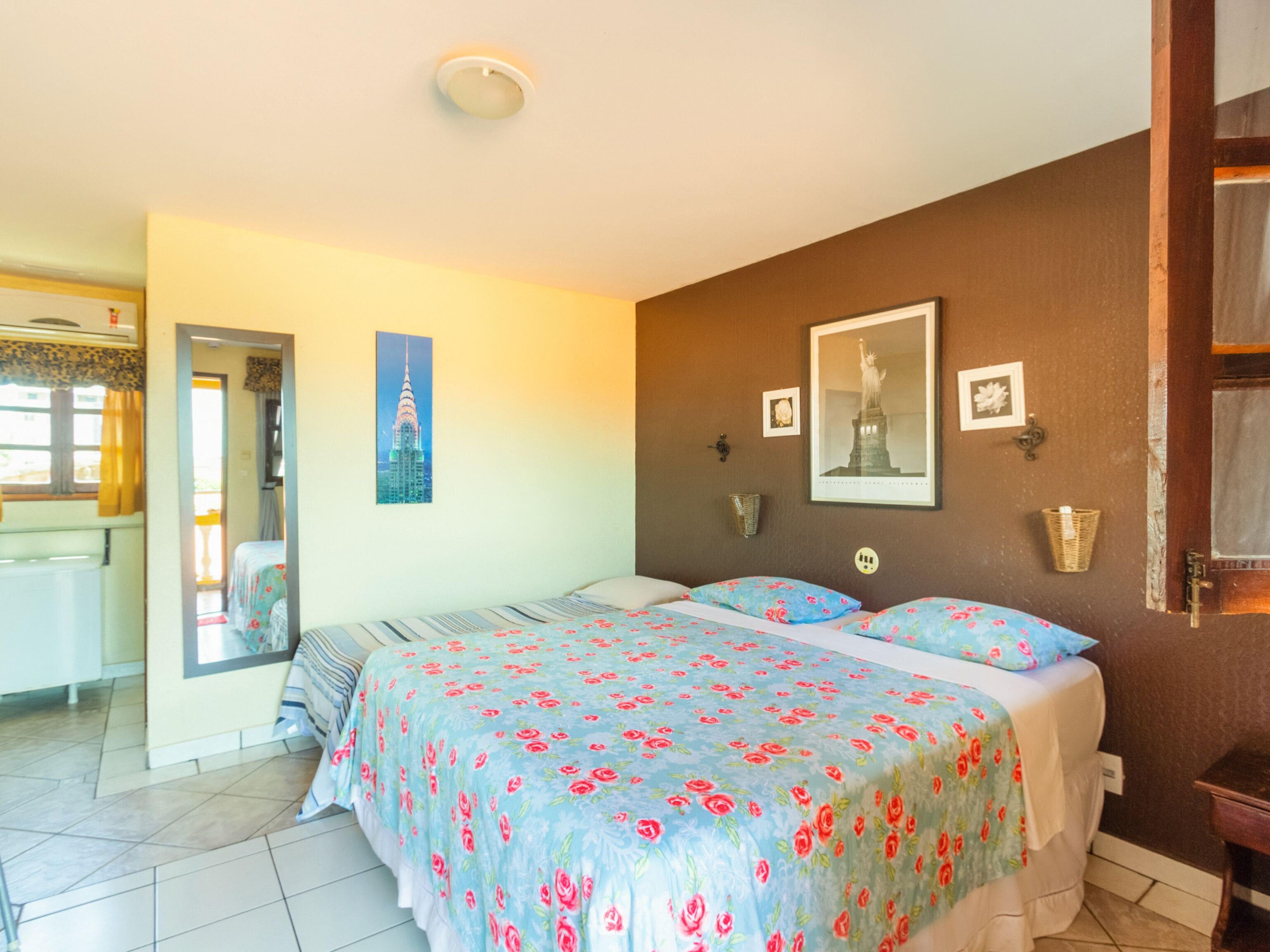 A bedroom with a bed, a dresser, a nightstand, and a door leading to another room.