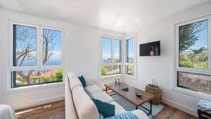 A modern living room with a large sofa, a wooden coffee table, and a TV mounted on the wall. - Quinta D'Alegria by Our Madeira (Funchal)