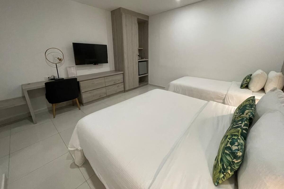 Un dormitorio moderno con dos camas, televisión, escritorio y armario.