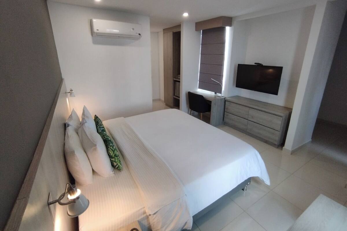 Habitación de hotel moderna con una cama grande, un escritorio, un televisor y un equipo de aire acondicionado.