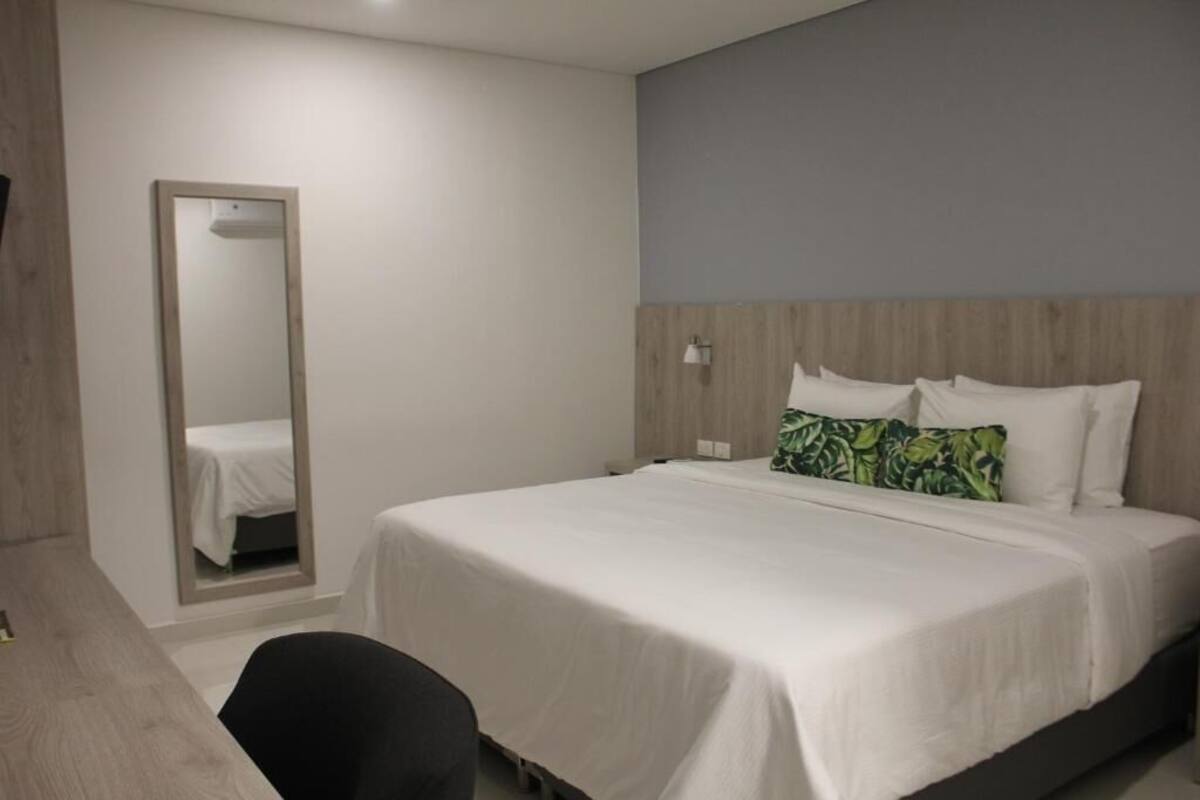 Una habitación de hotel con una cama, un escritorio y un espejo.