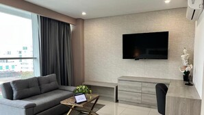 Uma sala de estar moderna com um sofá cinzento, uma mesa de centro com um laptop, uma televis ão de tela plana na parede e um armário minimalista.