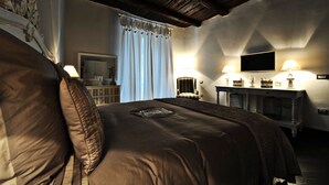 A bedroom with a large bed, a dresser, a television, and two lamps.
