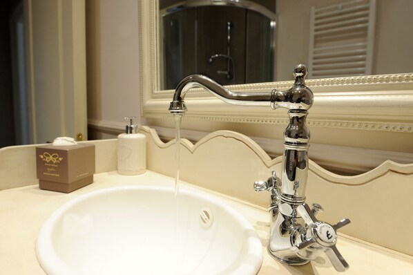 A bathroom sink with a chrome faucet, a mirror, and a tissue box on the counter. - B&B La Garçonniere (Salerno)