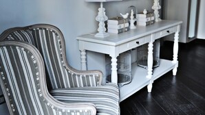 A striped chair and a white console table with lamps and decorative items.