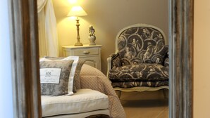 A bedroom with a bed, nightstand, lamp, and patterned armchair.