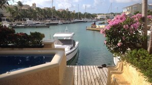 A marina with boats docked, a wooden deck, and a pool. - Holiday Home at 163 Port St Charles (Speightstown)