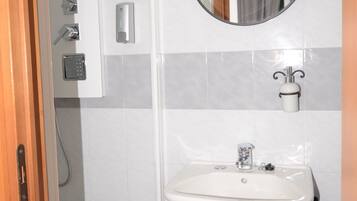 A bathroom with a shower, a sink, a mirror, and a towel rack.