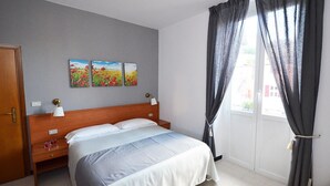 Een slaapkamer met een bed, nachtkastje, lamp en een schilderij aan de muur.