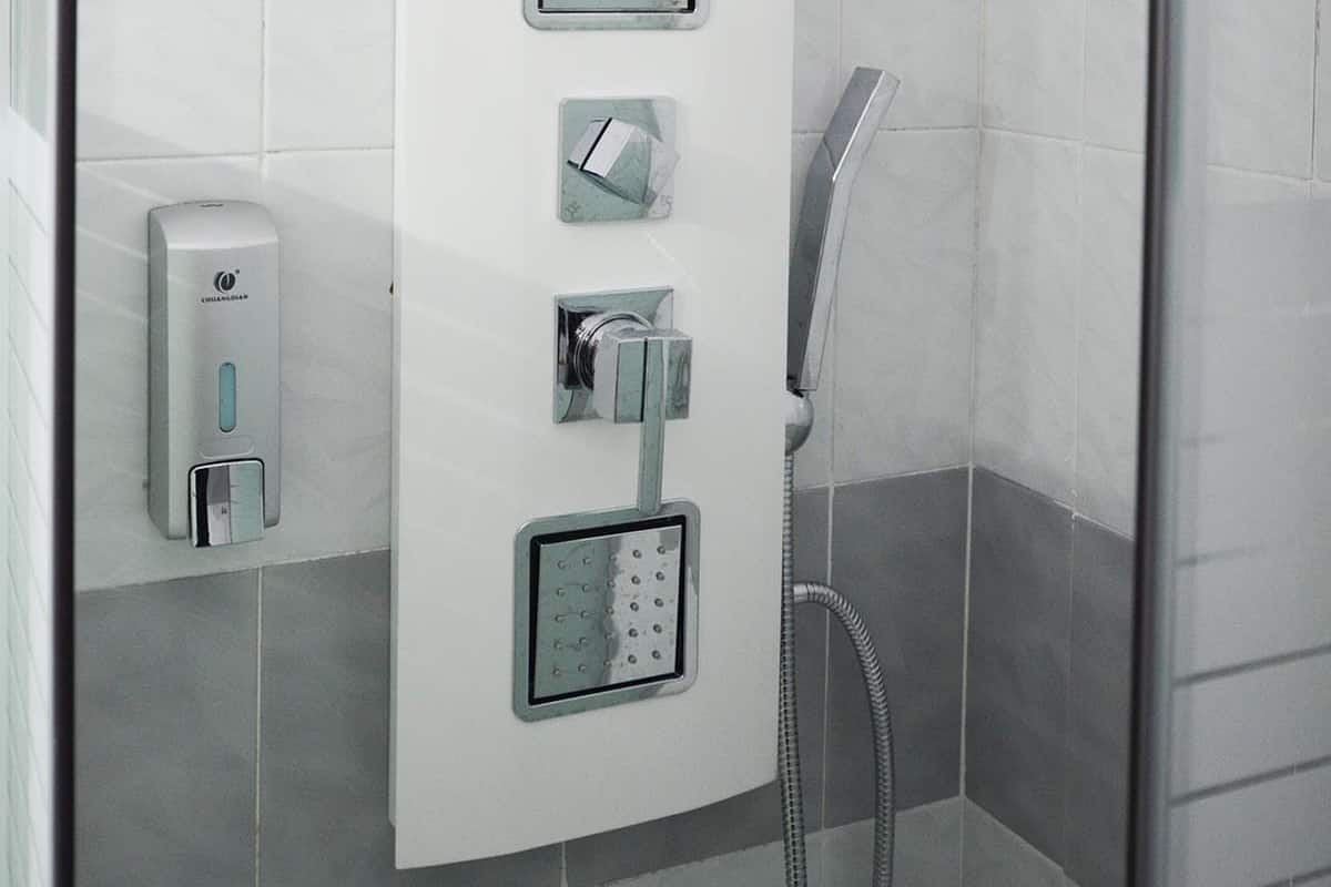 A shower with a handheld showerhead, a handheld showerhead, and a wall-mounted showerhead.