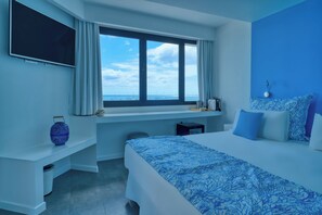 A hotel room with a large bed, a desk, a chair, a TV, and a window with a view of the sea. - Hotel Boutique La Marquesina Adults Only (La Oliva)