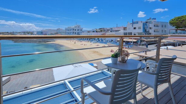 A balcony with a view of a beach and buildings. - Hotel Boutique La Marquesina Adults Only (La Oliva)
