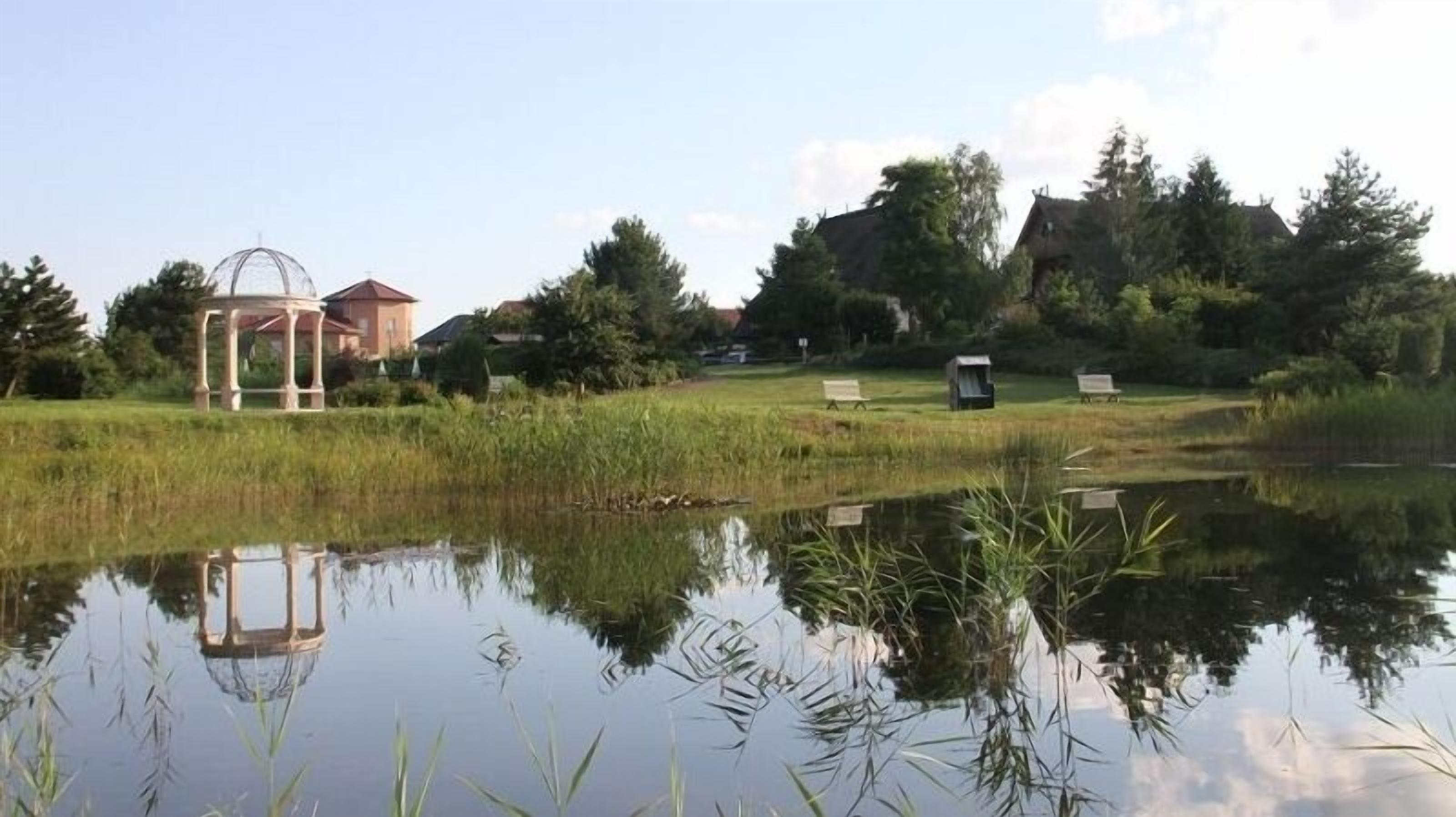 Eine friedliche Außenanlage mit einem Pavillon, einem Teich und einer Picknickgelegenheit.