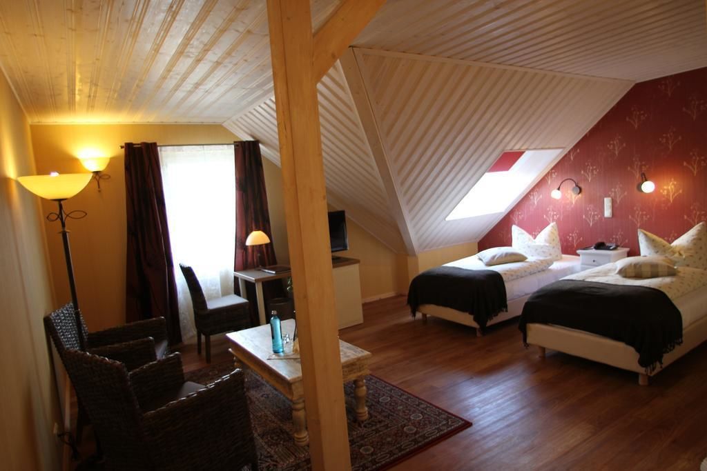 A cozy room with a sloped ceiling, two beds, a desk, and a chair.