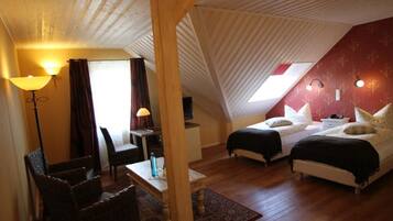 A cozy room with a sloped ceiling, two beds, a desk, and a chair.