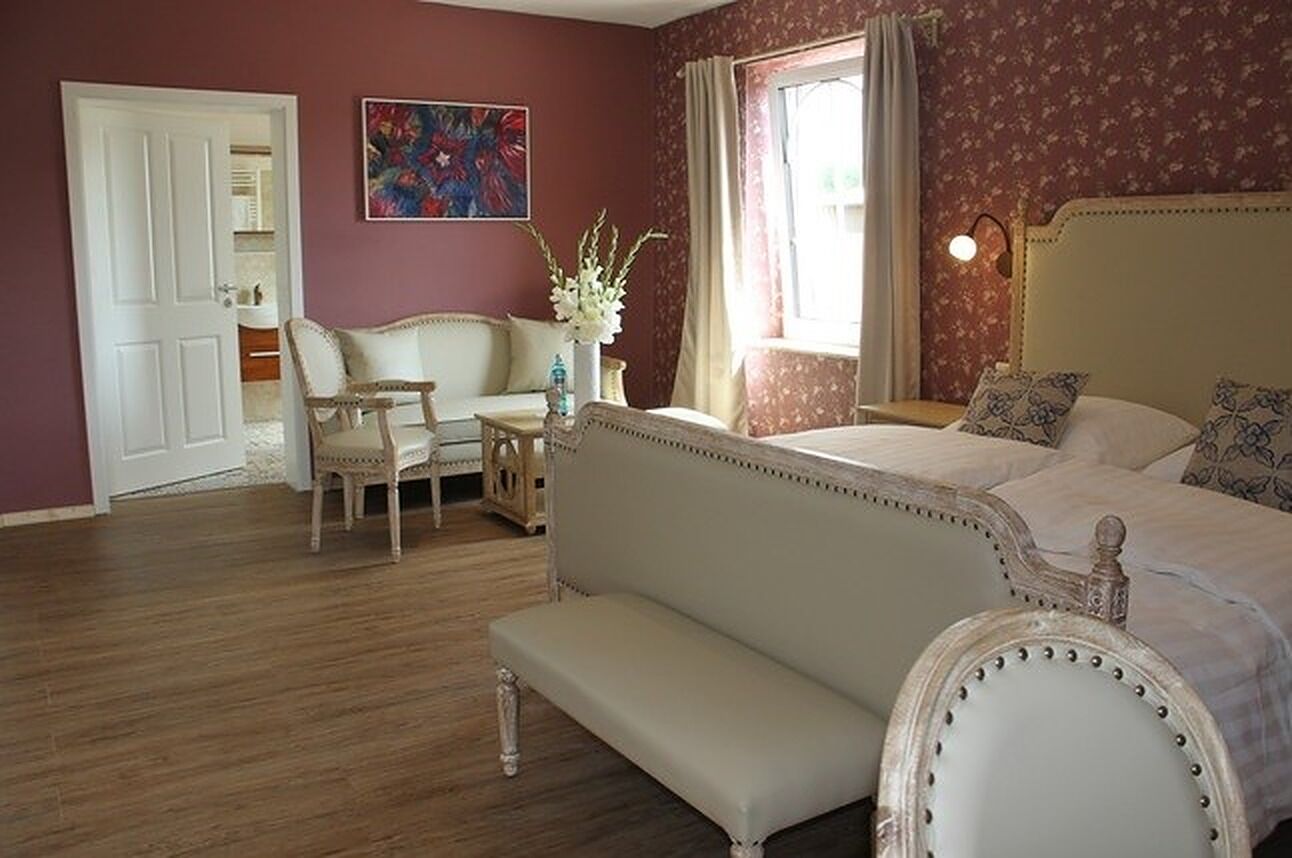 Un dormitorio con una cama, un banco, una silla y una mesita.