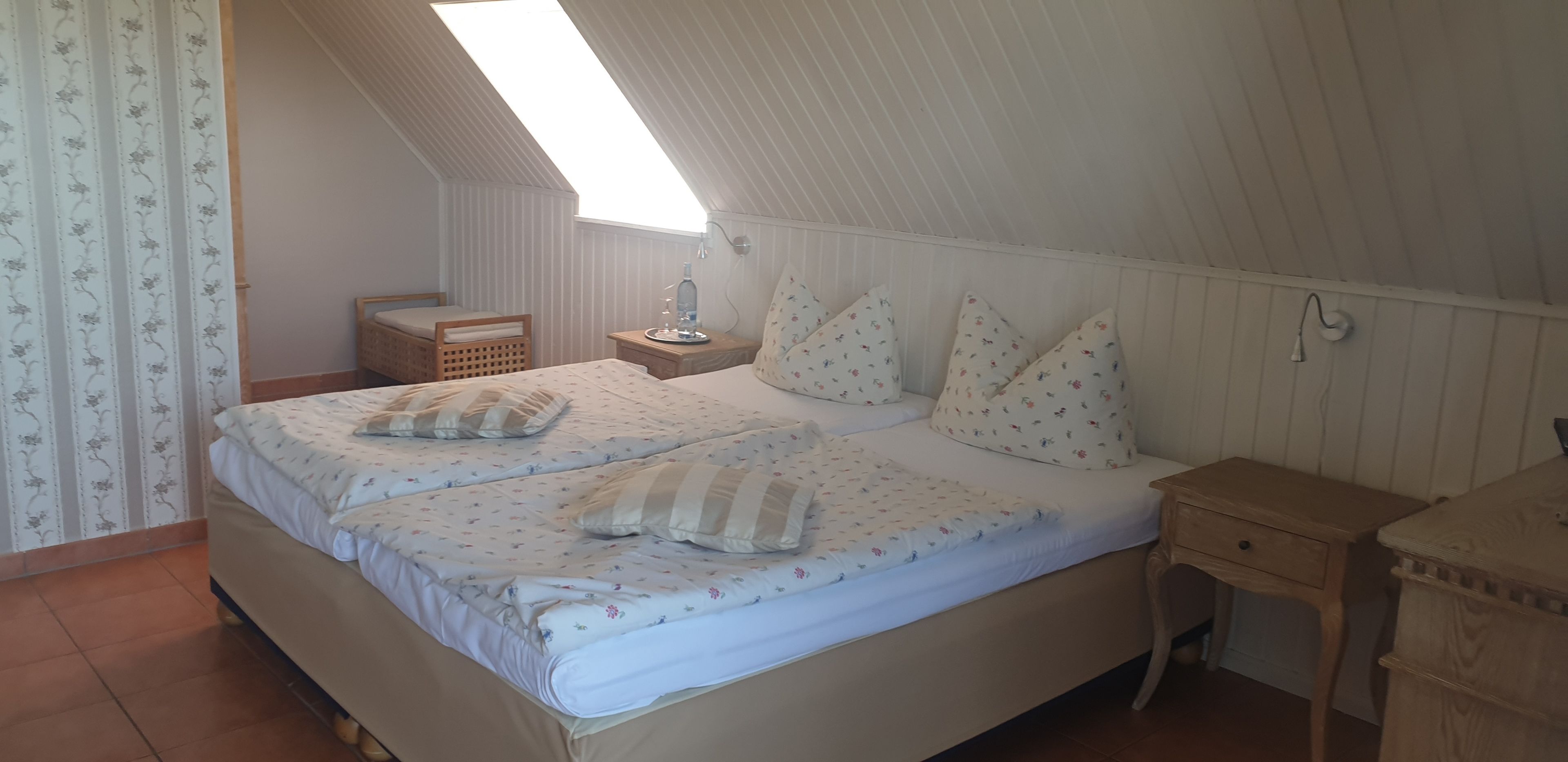 Un dormitorio con dos camas, una mesita de noche de madera, una pequeña mesa y una ventana con vistas.