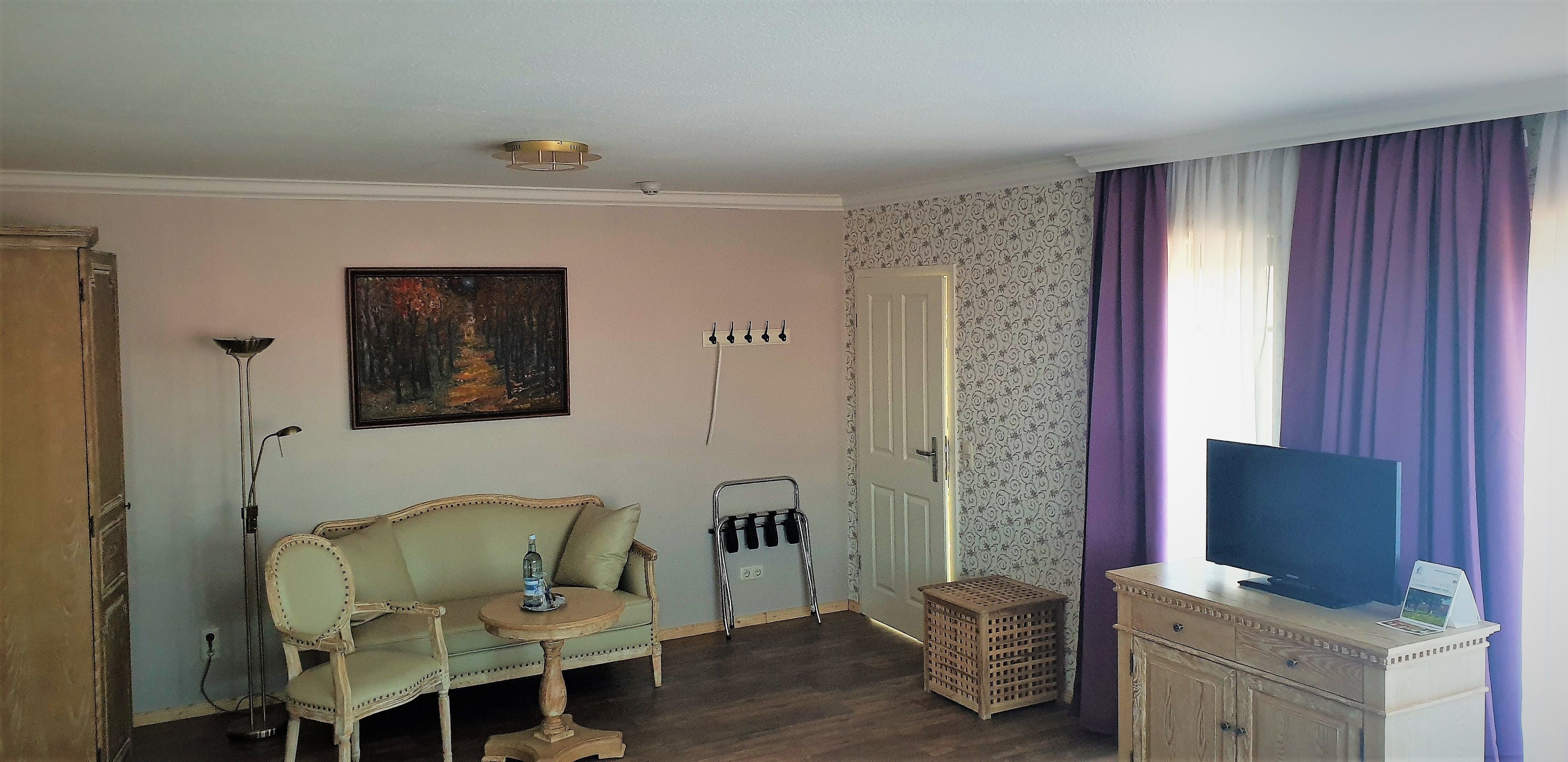 Una habitación con sofá, una mesita, televisor, lámpara y una puerta.
