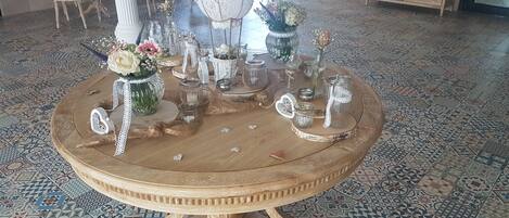 Une table ronde en bois, agrémentée d’un élément décoratif au centre, entourée de chaises et posée sur un sol à motifs.
