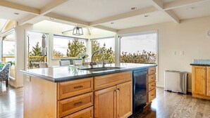 A modern kitchen with a large island, wooden cabinets, and a view to the outdoors. - Pritchard's Perch - private 2.5 acre in-city property, views from every room! (Seattle)