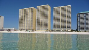 A beachfront hotel with multiple high-rise buildings, clear blue water, and a sandy beach.