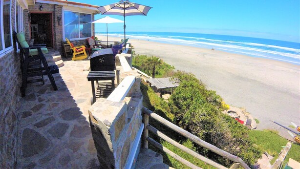 Een balkon met uitzicht op het strand, straatmubilair en een barbecue.