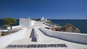 Un camino costero que lleva a edificios blancos, con vistas al mar.