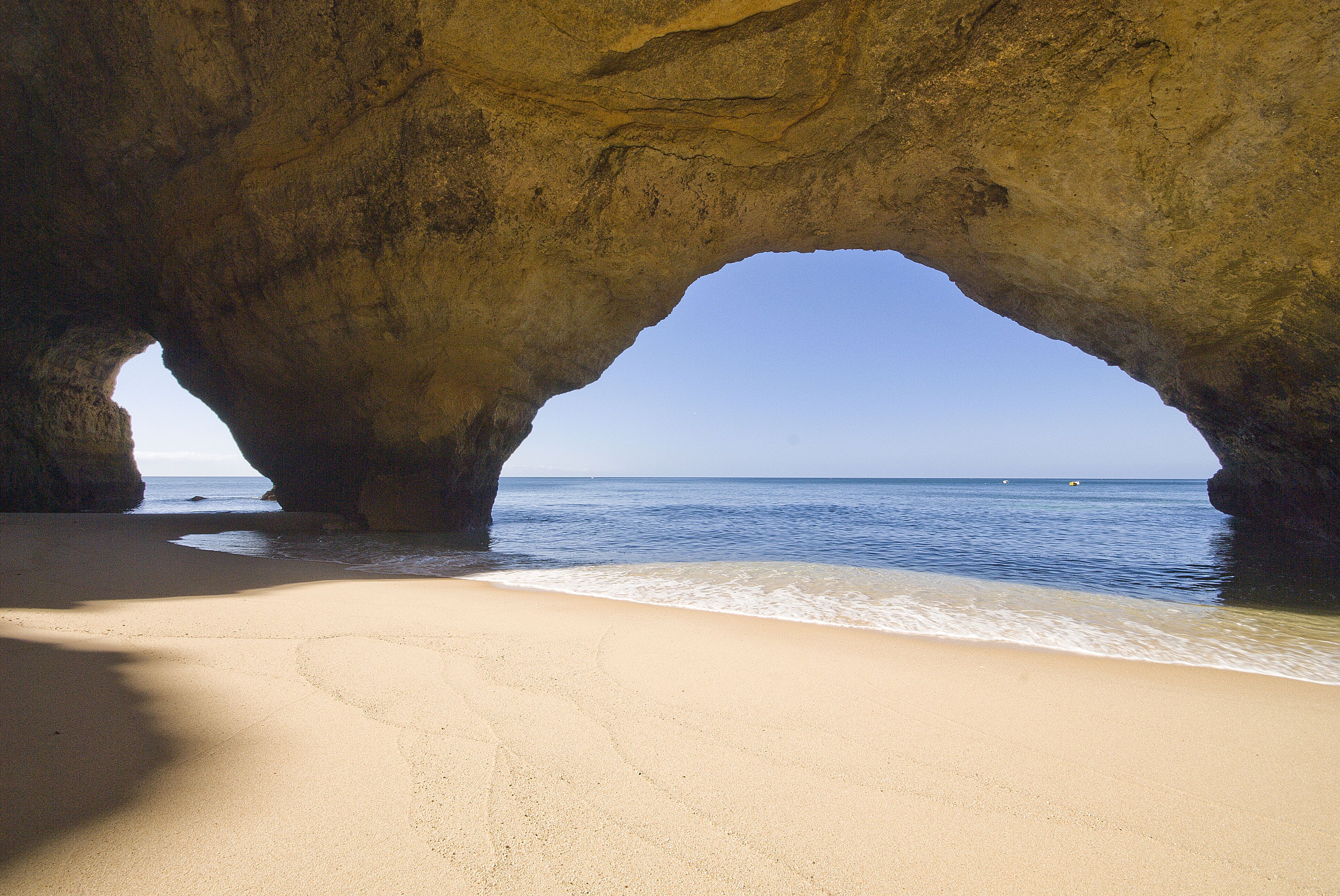 A beach with a natural rock arch formation.