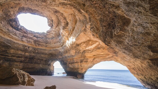 Formación rocosa natural con un gran arco sobre una playa.