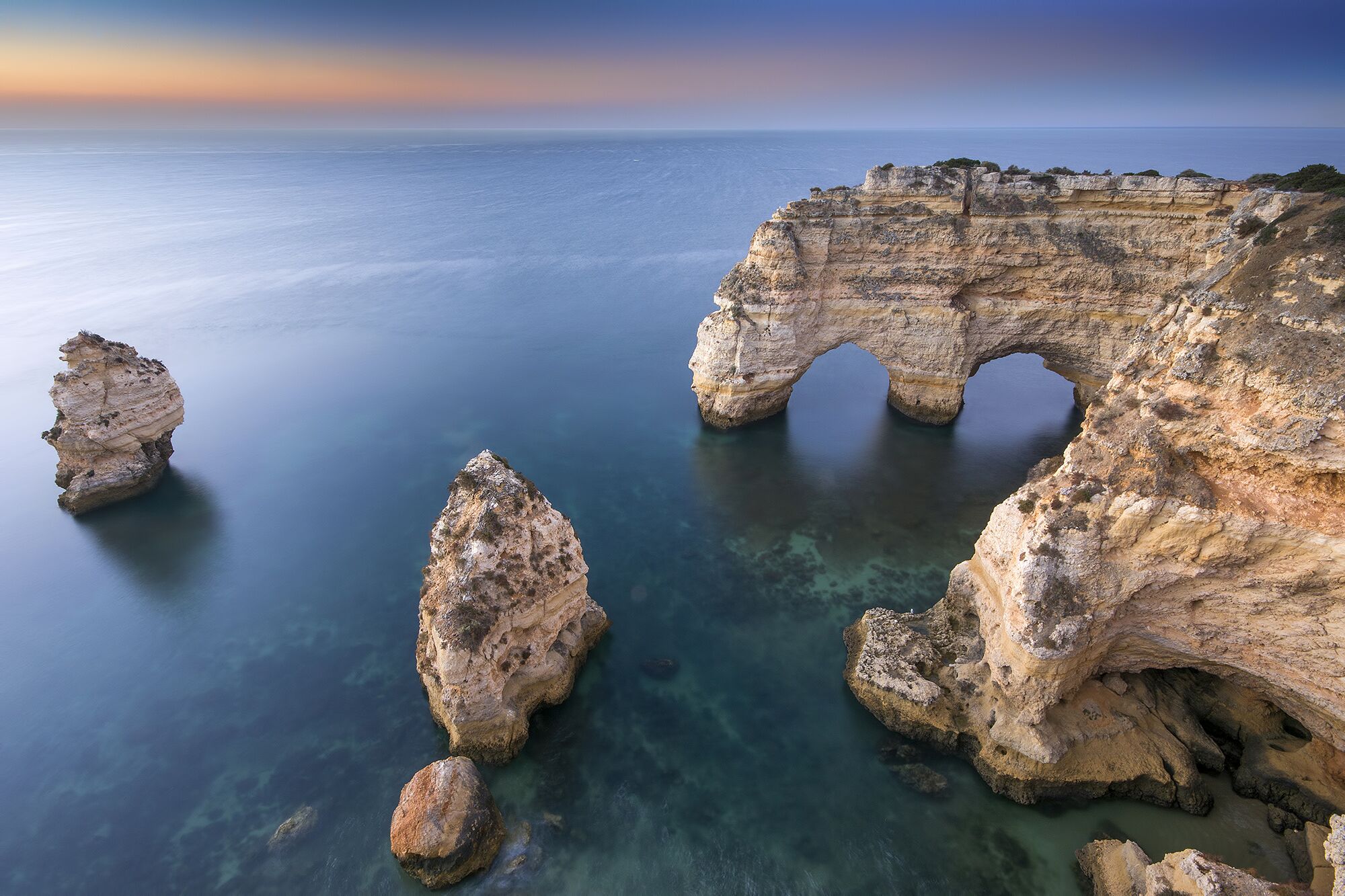 Un paysage côtier caractérisé par une formation rocheuse imposante, notamment une arche naturelle.