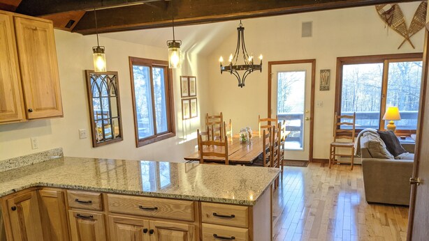 Una cocina amplia con armarios de madera, encimeras de granito y una zona de comedor con mesa y sillas de madera.