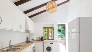 Una cucina moderna con mobili bianchi, piani in legno, una lavatrice integrata e un'ampia finestra con vista sul verde.