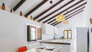 Una cucina moderna con mobili bianchi, un'isola centrale e un'area pranzo con un tavolo bianco e sedie rosse.