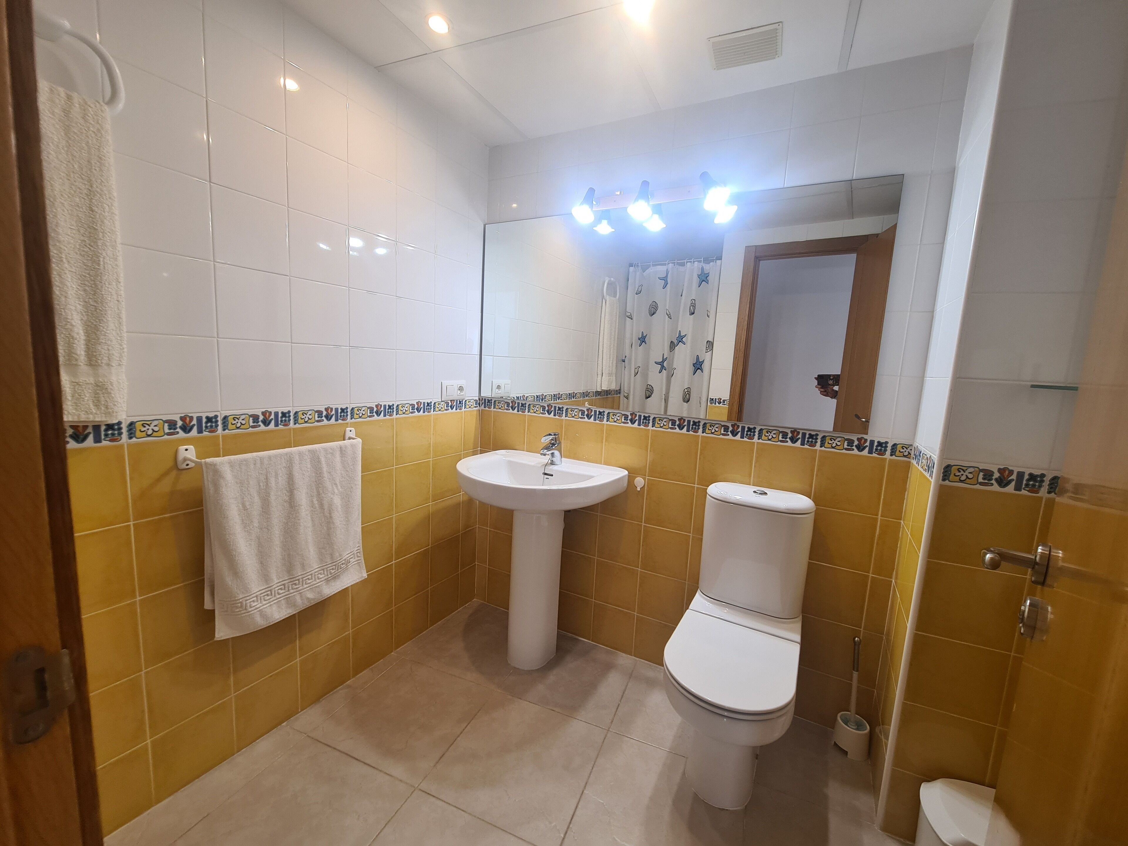 A bathroom with a white sink, toilet, and a mirror.