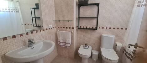 A bathroom with a sink, two toilets, a mirror, and a towel rack.
