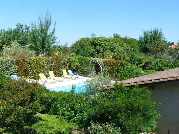 A pool area with lounge chairs and a pergola.