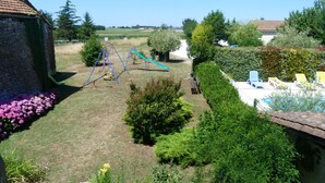 Ein Garten mit Schaukel, kleinem Pool und einem Steinhaus.
