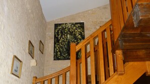 Eine Holztreppe mit Handlauf, ein gerahmtes Bild an der Wand und eine Heizung auf dem Boden.