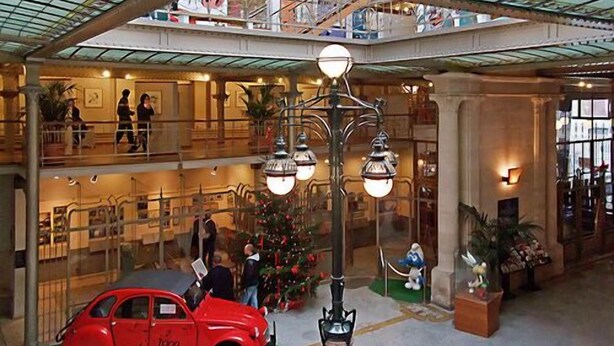 Ein mehrgeschossiges Atrium mit einem roten Auto, einem Weihnachtsbaum und einer Statue.