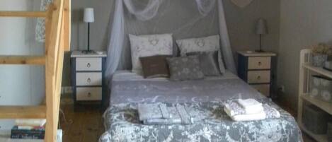 A bunk bed room with a wooden ladder, a canopy bed, bedside tables, and a small shelf.