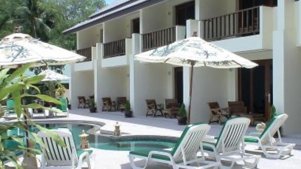 A pool area with lounge chairs and umbrellas, a building with a balcony, and a clear sky. - Apartment/ flat - Koh samui (Koh Samui)