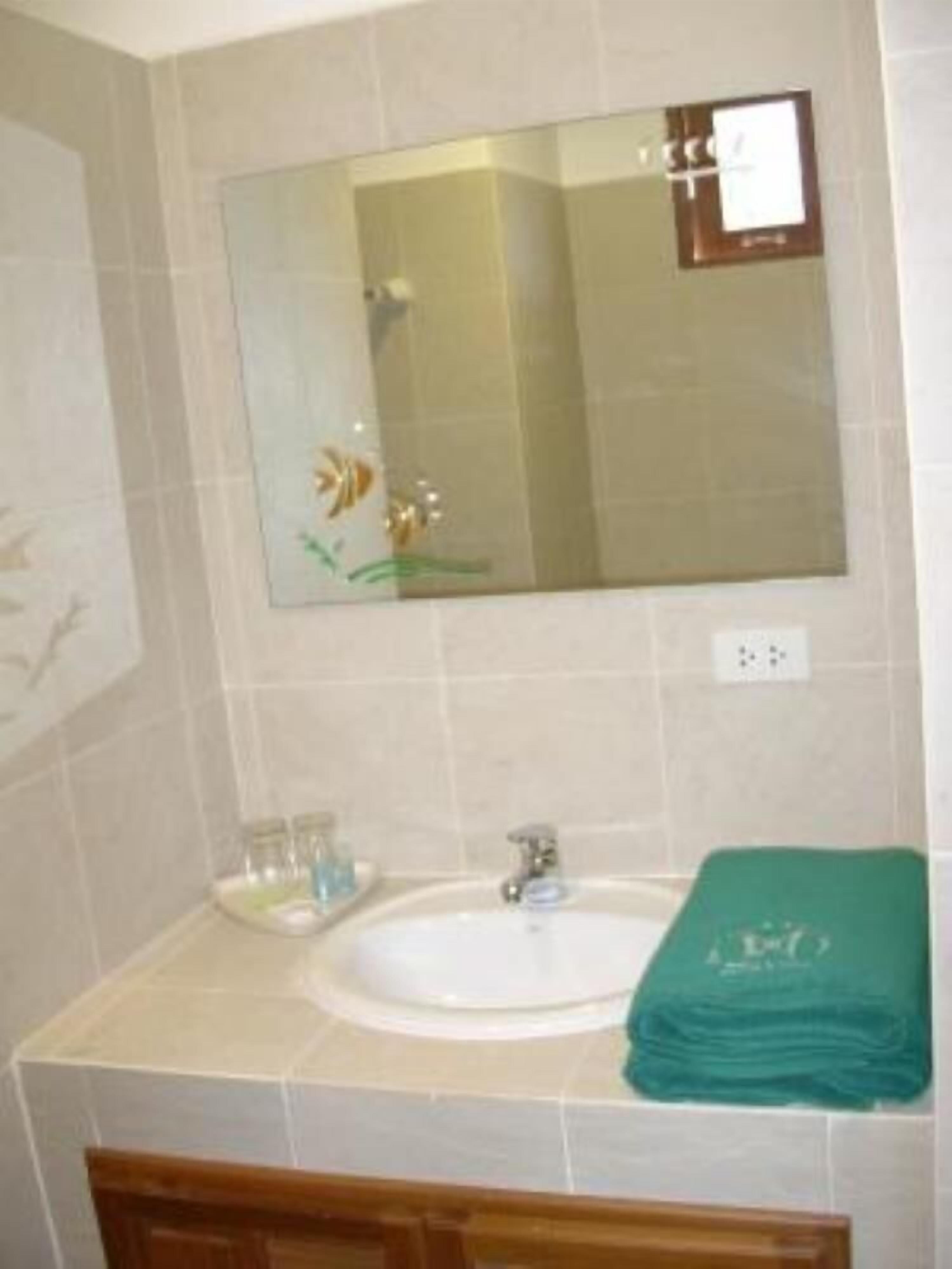A bathroom with a sink, mirror, and green towel.