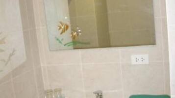 A bathroom with a sink, mirror, and green towel.