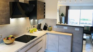 A modern kitchen with a built-in stove, a bowl of fruit, and a coffee maker. - Generous exclusive holiday home in a dream location right on the beach with great views (Gruissan)